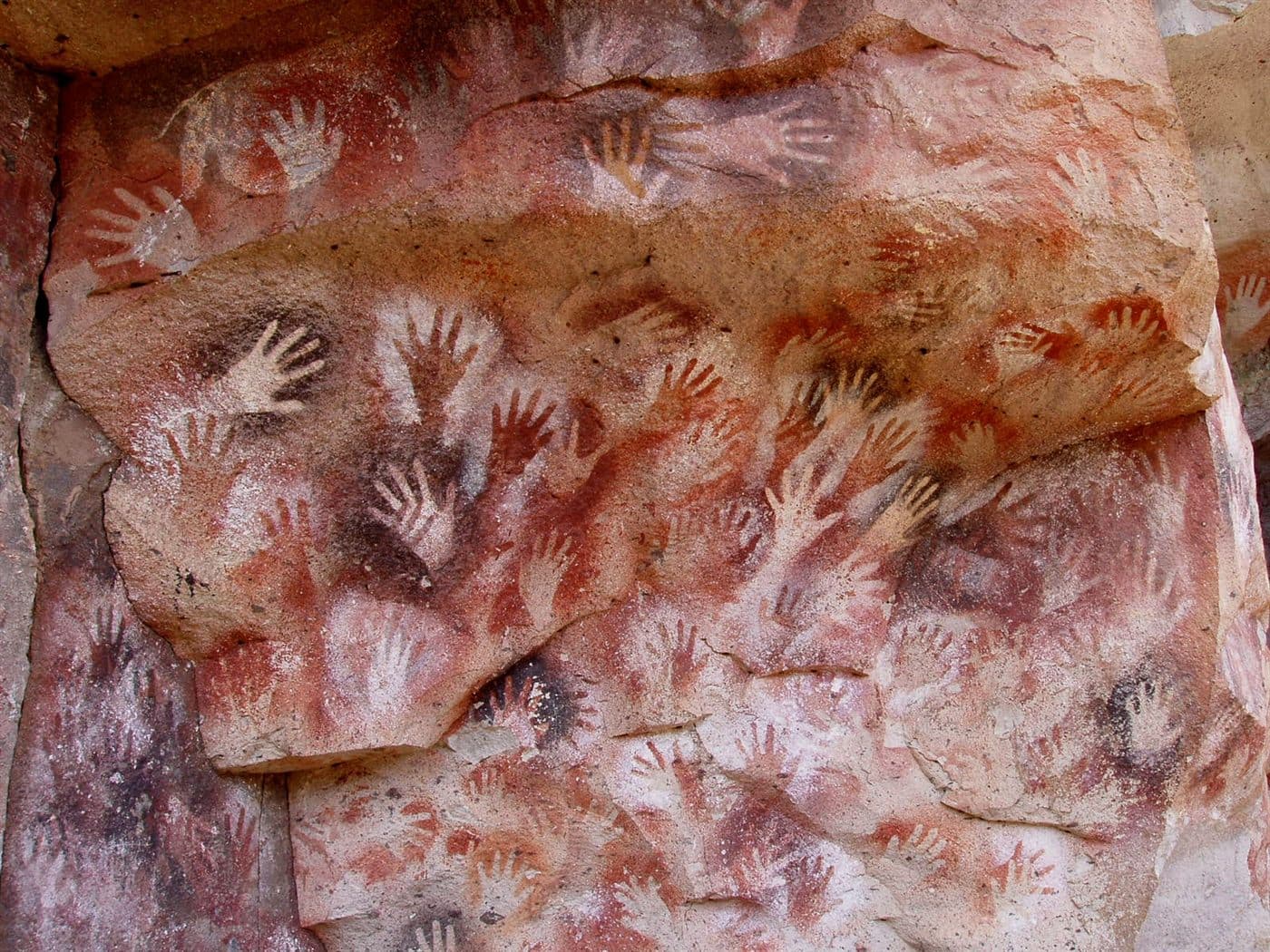 Hundreds of painted hand stencils covering the rock wall of Cueva de las Manos in Patagonia